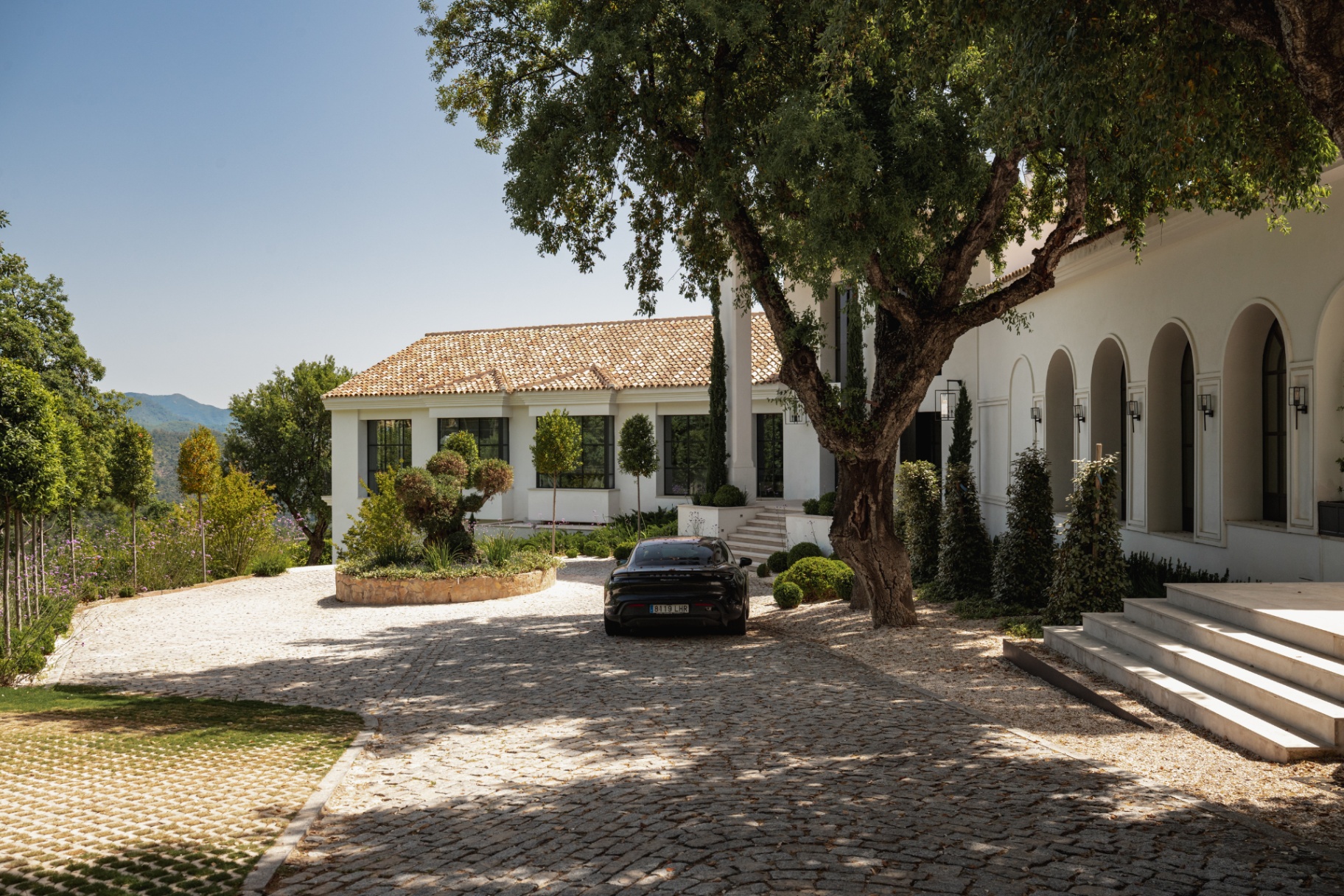 The circular entrance court at Casa Servetta with a fountain and mature trees.